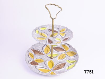 1960s two tier cake stand with gilt metal handle and rod Made at the Old Foley potteries by James Kent ltd England Acid & detergent proof colours Bottom plate measure 225mm in diameter & top measures 160mm in diameter Photo of stand from a raised angle showing pattern on both plates with foliage pattern in yellow, orange and brown