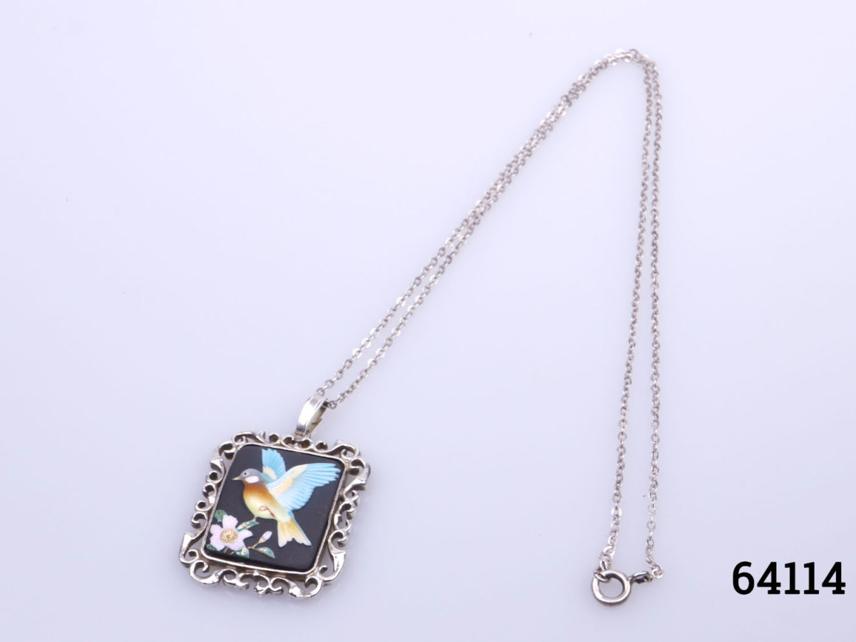 c1978 Hand-painted porcelain pendant by Toshikane of Japan mounted on a silver frame and sterling silver chain. Pendant frame fully hallmarked for Birmingham assay. Pendant measures 35mm long from top of bail to base and 25mm wide. Photo of necklace and pendant laid on a flat surface