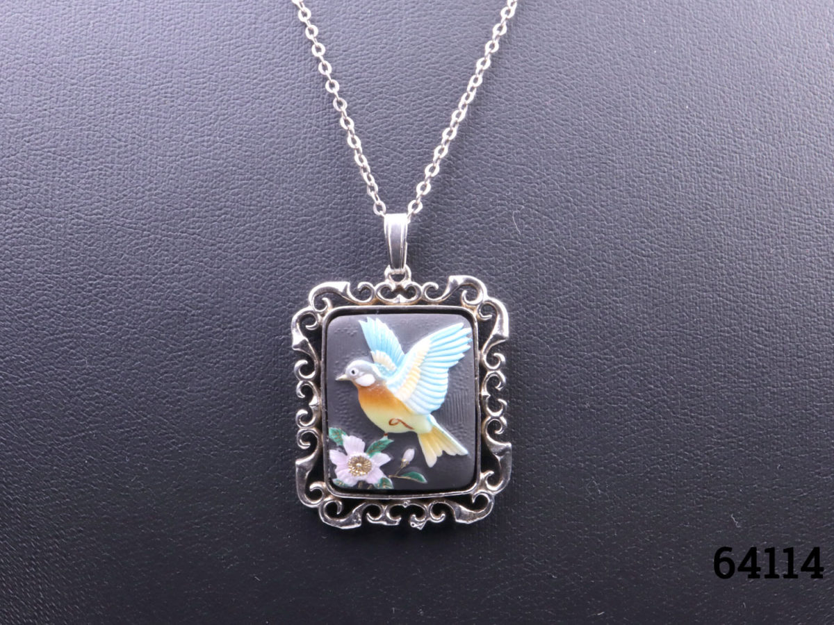 c1978 Hand-painted porcelain pendant by Toshikane of Japan mounted on a silver frame and sterling silver chain. Pendant frame fully hallmarked for Birmingham assay. Pendant measures 35mm long from top of bail to base and 25mm wide. Close up photo of the pendant showing hand-painted bird with flower