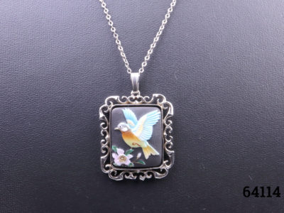 c1978 Hand-painted porcelain pendant by Toshikane of Japan mounted on a silver frame and sterling silver chain. Pendant frame fully hallmarked for Birmingham assay. Pendant measures 35mm long from top of bail to base and 25mm wide. Close up photo of the pendant showing hand-painted bird with flower