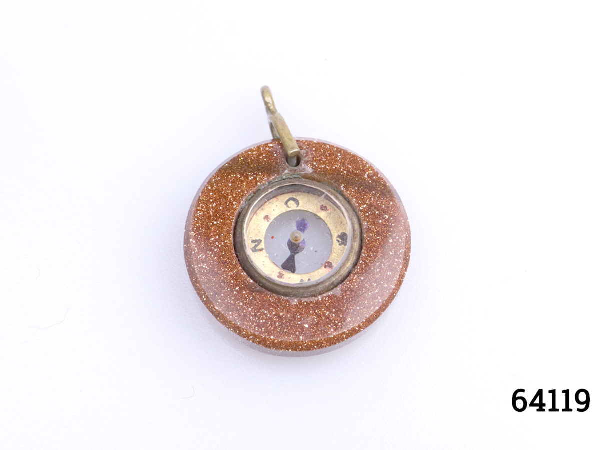 Antique goldstone compass fob. Miniature compass set in a ring of sparkly goldstone and mounted on brass. Comes in box and pouch. Measures 20mm in diameter and weighs 3.6g. Main photo showing fob with clasp to the top