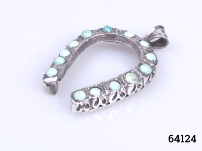 Vintage Egyptian silver horseshoe pendant. Lucky horseshoe encrusted with small turquoise bead stones all the way round. Drop length 45mm from bail Photo of pendant at a diagonal angle with bail to top right and shoe ends at bottom left