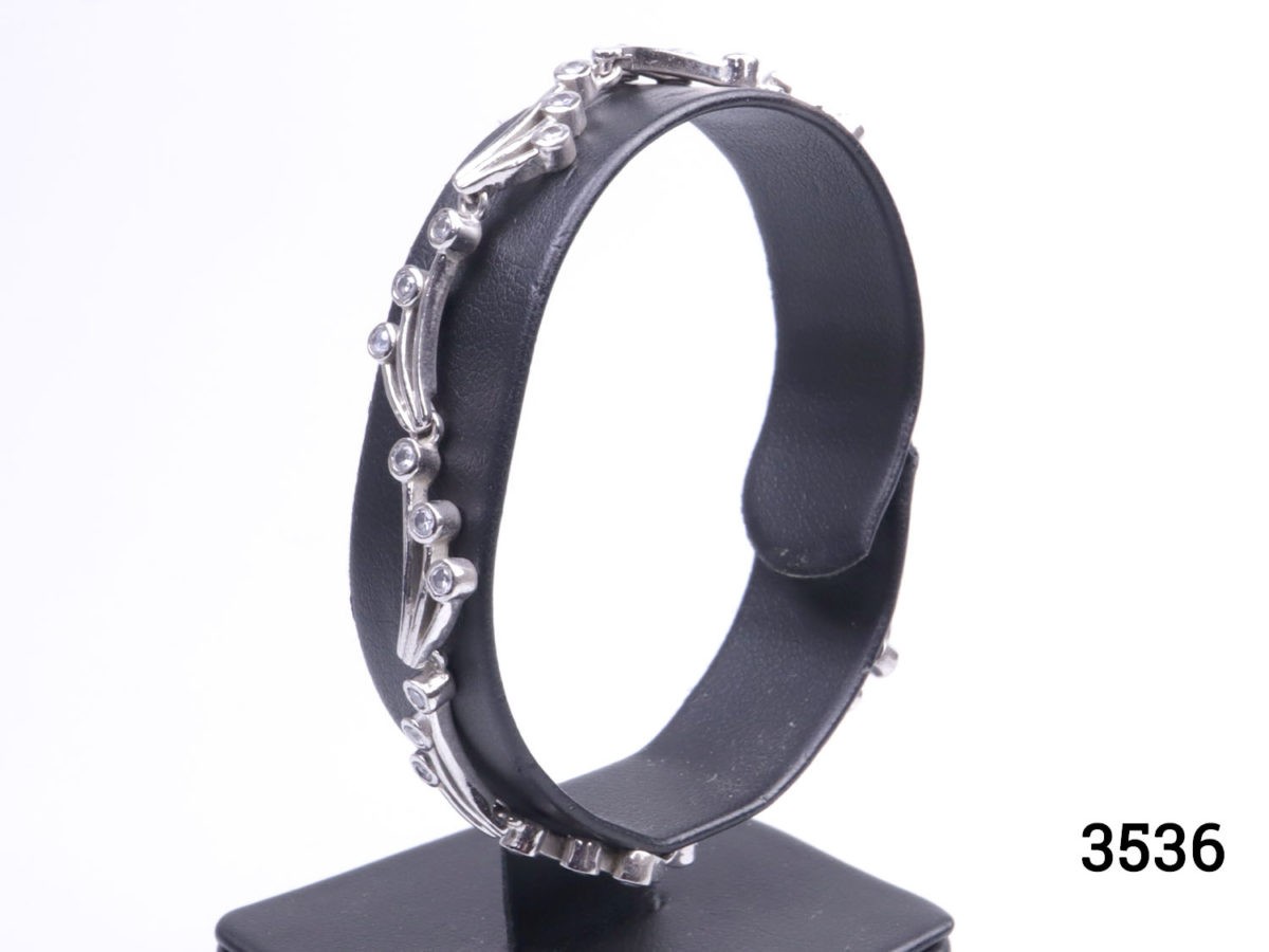 Vintage 925 sterling silver bracelet set with small cubic zirconia pieces in a wave like form. Hallmarked 925 Photo of bracelet on display stand seen from a side angle