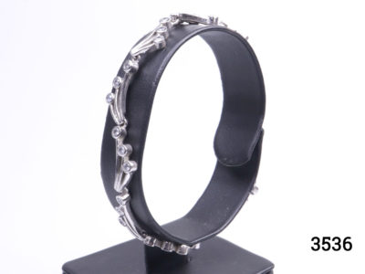 Vintage 925 sterling silver bracelet set with small cubic zirconia pieces in a wave like form. Hallmarked 925 Photo of bracelet on display stand seen from a side angle