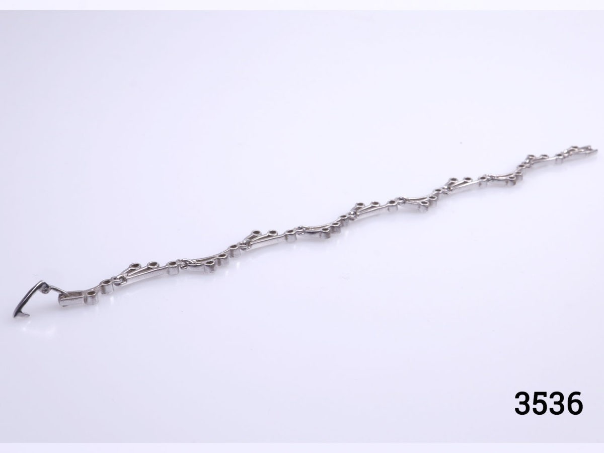 Vintage 925 sterling silver bracelet set with small cubic zirconia pieces in a wave like form. Hallmarked 925 Photo of bracelet on a flat surface showing the back