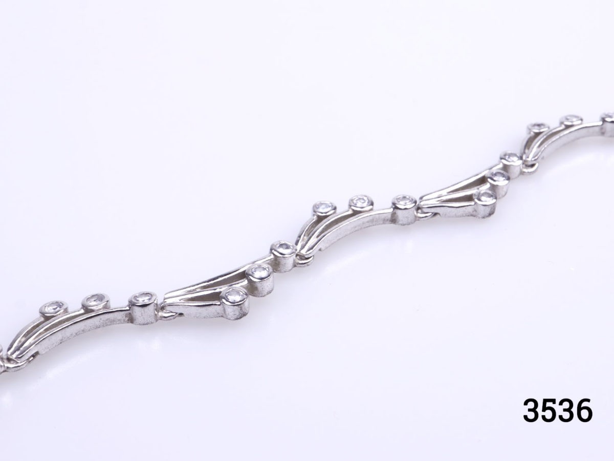Vintage 925 sterling silver bracelet set with small cubic zirconia pieces in a wave like form. Hallmarked 925 Close up photo of bracelet on a flat surface focusing on part of wavy pattern
