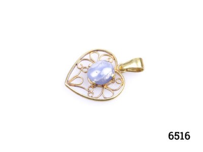 Vintage 18 karat gold heart pendant set with a star sapphire cabochon to the centre. Hallmarked GH18k on the pendant bail. Drop length 25mm Photo of pendant on a flat surface seen from a side angle with bail to the right