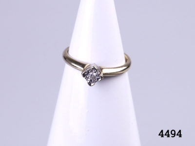 Vintage 9 karat gold ring with a small round cut diamond set on a white gold head.  Ring size M / 6. Ring weight 1.8 grams. Main photo of ring displayed on a stand and seen from the front.