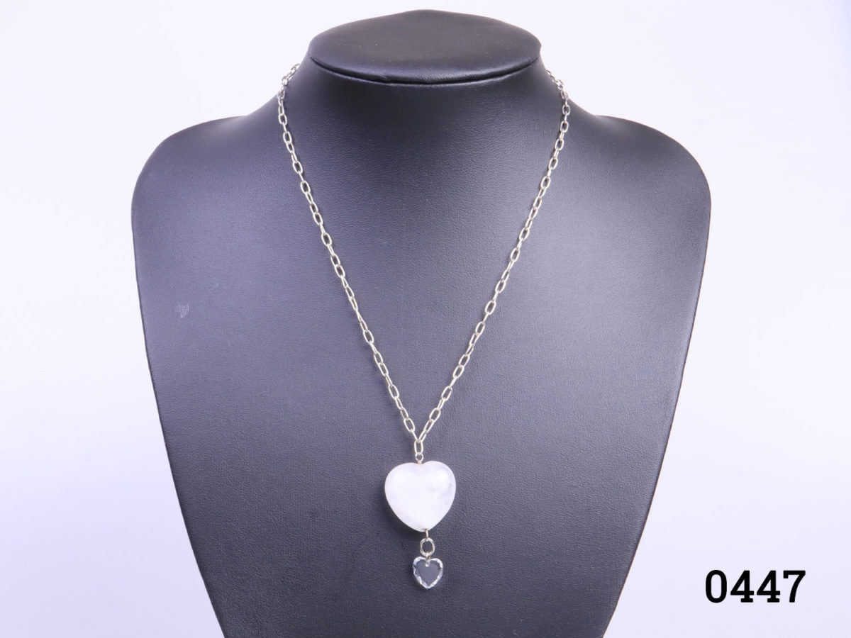 925 Sterling silver chain with a rock quartz crystal heart. A smaller clear crystal heart attached below the quartz heart. Pendant drop length 43mm. Main hoto of necklace on a display stand looking straight on