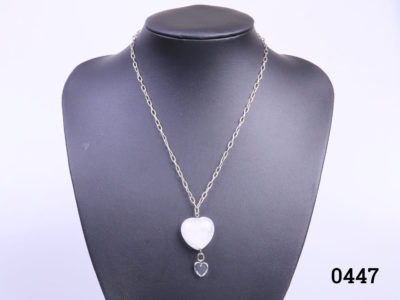 925 Sterling silver chain with a rock quartz crystal heart. A smaller clear crystal heart attached below the quartz heart. Pendant drop length 43mm. Main hoto of necklace on a display stand looking straight on
