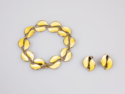Vintage David Andersen silver and enamel set. Gilt sterling silver and yellow enamel leaf set consisting of clip-on earrings and bracelet. Enamel in excellent order on all pieces. The earring clips are in good working order with the clip part made of metal. Earring front measures approximately 20mm by 15mm. Bracelet measures 85mm in length.  Main photo of bracelet and earrings laid side by side on a flat surface