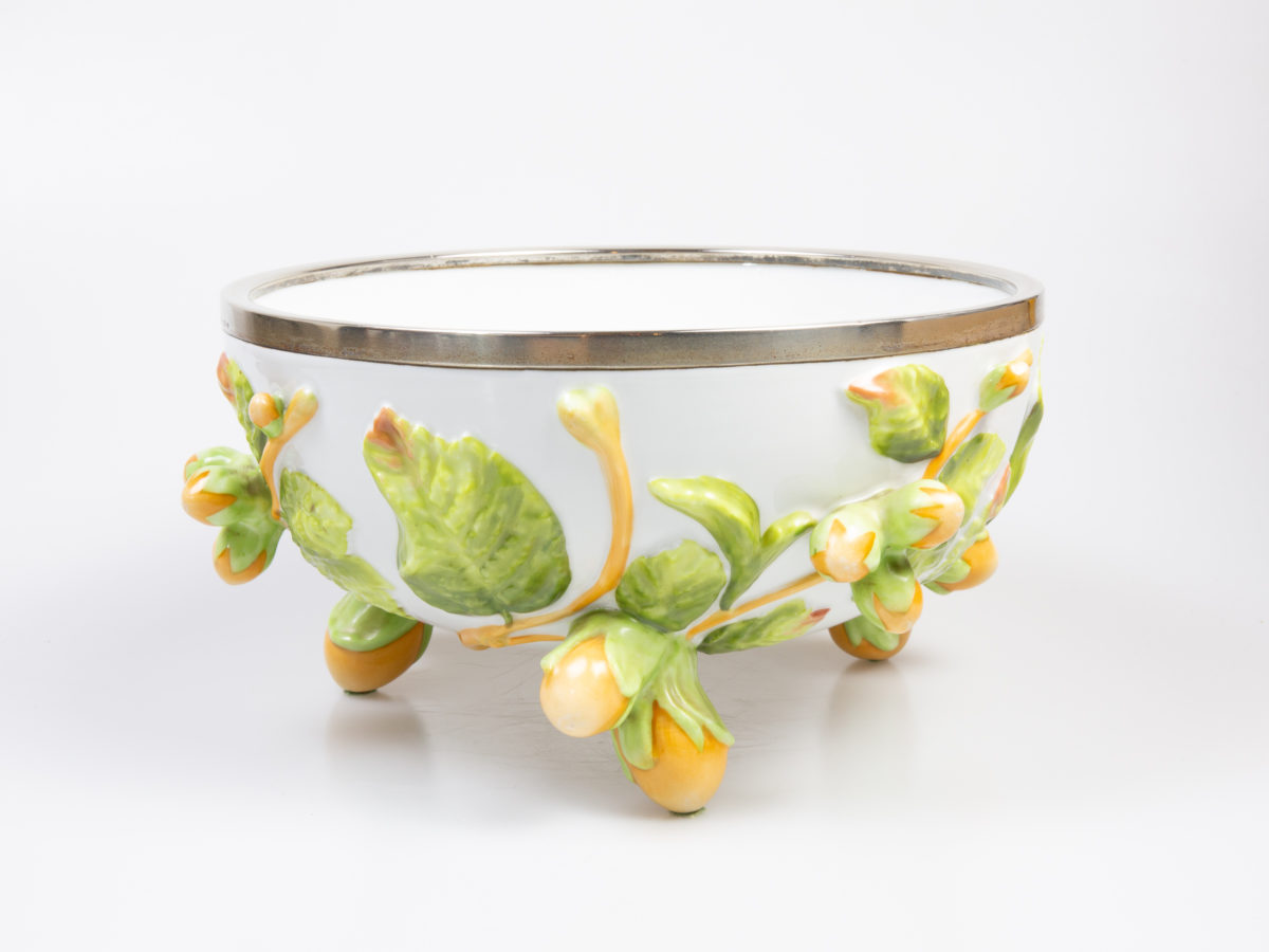 Antique Geman Musterschutz bowl. Large porcelain bowl with embossed decoration of hazelnuts and leaves with the 3 feet also in the form of hazelnuts. Silver plate rim is hallmarked WMFN (Wurttemburgische Metallwarenfabrik Neusilber) with antler and letter O in rhombus. Stamped Musterschutz with the number 30 on the base. Very small dent and slight discolouration of the silver plate rim. Porcelain bowl is in excellent condition with only one very small chip below the silver rim. c1900 Measures approximately 150m apart each foot and 217mm in diameter across the top. Main photo of bowl from an eye level angle shown with one hazelnut foot in the middle of foreground