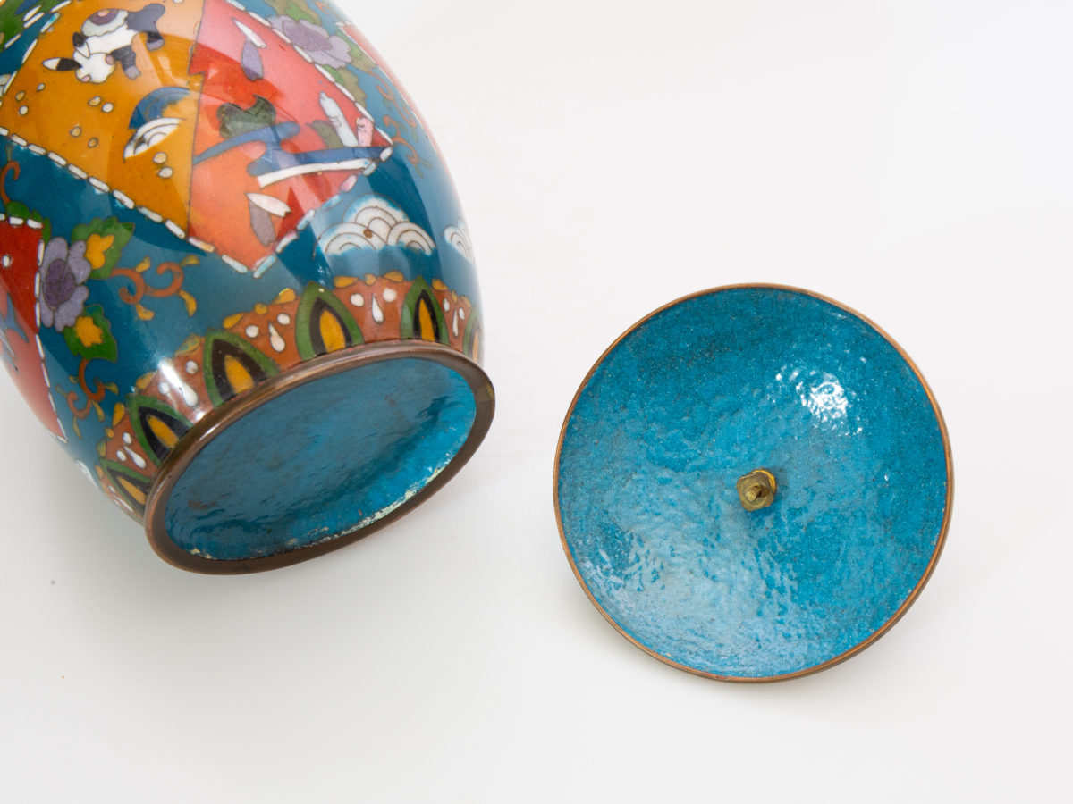 Early 20th century lidded cloisonne jar. Good sized jar in unusually muted colours for cloisonne which adds to the attractiveness of the jar. Decorated with flora and fauna to the side. Enamel in excellent condition. Finial is a little loose on the lid & needs attention. Measures 88mm in diameter at base, approximately 120mm in diameter at widest part and 165mm tall with lid. Close up photo of the inside of lid and base of jar