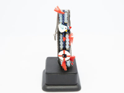 Costume jewellery bracelet with seagulls. Lovely bracelet depicting a seaside theme with 2 seagulls in sailing caps on either side of a life ring. Blue crystals gives it an 'at sea' look with nice blue and red thread work to accentuate the design. Interesting clasp with safety chain closure. Made in France by Taratata. Bracelet width approximately 20mm. Main photo of bracelet on a display stand showing only one seagull and life ring