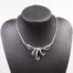 Vintage Trifari collar necklace. Glamorous collar necklace encrusted with clear and blue rhinestones with a ribbon like effect to the front. Signed Trifari to the clasp and marked patent pending. Necklace front measures 35mm at widest point in the middle of ribbon-like effect. Not adjustable. Main photo of necklace on a dark display stand