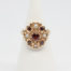 Vintage 9 karat gold ring with garnets and seed pearls. c1959 London assayed 9 karat gold ring with round cut garnet to the centre surrounded by 4 small garnets and seed pearls set on heart shaped petals with leaves on shoulders. Ring size O.5 / 7.75 Ring front measures approximately 18mm by 16mm. Main photo of ring on a display stand shown from the front
