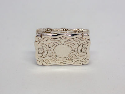 c1872 Victorian sterling silver vinaigrette. A sweet rectangular vinaigrette decorated on both sides with a vacant cartouche for personalisation. A flower decorates the inner grille. Fully hallmarked to the inside lid as well as lower section. Assayed in Birmingham by Frederick Marson. In excellent condition. Main photo of lid of vinaigrette with vacant cartouche shown