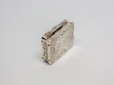 c1872 Victorian sterling silver vinaigrette. A sweet rectangular vinaigrette decorated on both sides with a vacant cartouche for personalisation. A flower decorates the inner grille. Fully hallmarked to the inside lid as well as lower section. Assayed in Birmingham by Frederick Marson. In excellent condition. Photo of vinaigrette on its side with opening side to the top