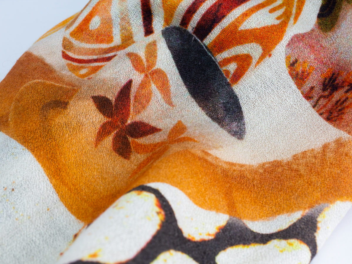 Modern hand-woven mixed fibre scarf. Luxurious hand-woven scarf in modal, wool, silk & cashmere-incredibly soft to the touch you can hardly feel it! Design is hand-printed using traditional methods of silk screen and lithographic wood block and shows pottery pieces with flowers. An absolutely gorgeous gift for someone special. Close up of another area of scarf design
