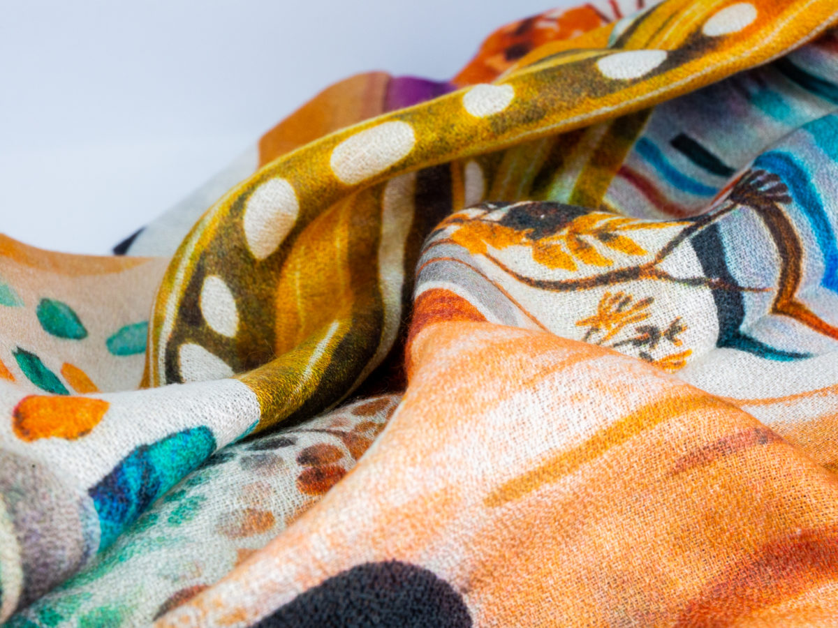 Modern hand-woven mixed fibre scarf. Luxurious hand-woven scarf in modal, wool, silk & cashmere-incredibly soft to the touch you can hardly feel it! Design is hand-printed using traditional methods of silk screen and lithographic wood block and shows pottery pieces with flowers. An absolutely gorgeous gift for someone special. Close up of a partial area of scarf showing the many varied patterns