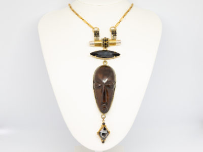 Modern necklace by designer Vicki Sarge. Fantastic statement necklace by famous designer Vicki Sarge in gold plate with Swarovski crystals and wood. The designer has been photographed wearing one very similar to this. Comes in original pouch and box and with original invoice. Drop length of pendant is 155mm, the wooden face measures 78mm. Necklace length is adjustable from 520mm at shortest to 570mm at longest. Main photo of necklace displayed on a white display stand focusing on the pendant hanging area.