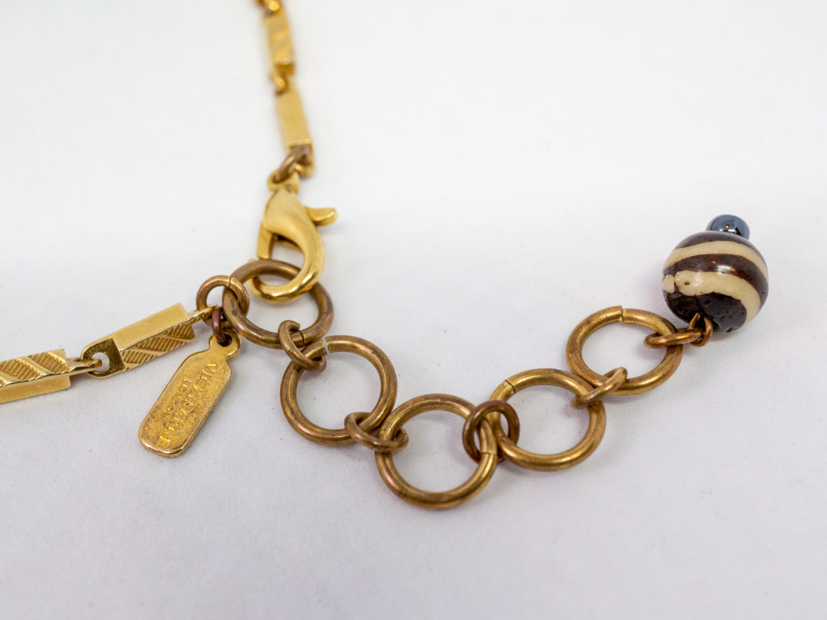 Modern necklace by designer Vicki Sarge. Fantastic statement necklace by famous designer Vicki Sarge in gold plate with Swarovski crystals and wood. The designer has been photographed wearing one very similar to this. Comes in original pouch and box and with original invoice. Drop length of pendant is 155mm, the wooden face measures 78mm. Necklace length is adjustable from 520mm at shortest to 570mm at longest. Close up photo of the makers tag to link of one of chains at clasp end of necklace.