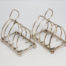 Pair of antique sterling silver toast racks. Small but sweet pair of toast racks. c1899 Birmingham assay and made by William Hutton. Each toast rack measures 72mm long, 47mm wide and 85mm tall at central point. Main photo showing both racks side by side and at a slight diagonal angle across the page.