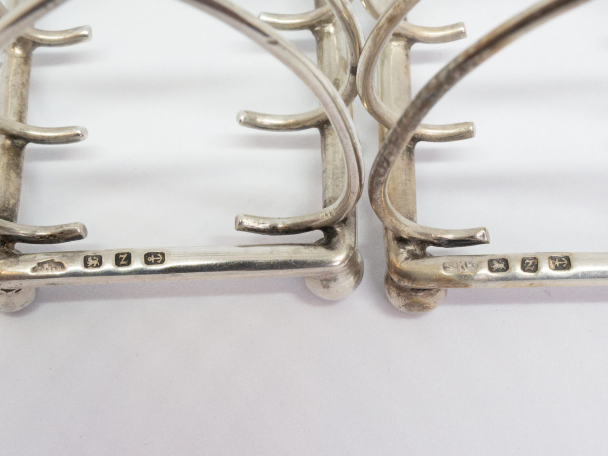 Pair of antique sterling silver toast racks. Small but sweet pair of toast racks. c1899 Birmingham assay and made by William Hutton. Each toast rack measures 72mm long, 47mm wide and 85mm tall at central point. Close up photo of the hallmarks to both racks.