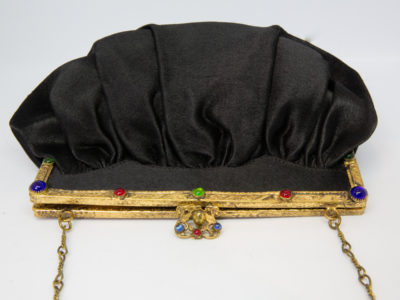 Vintage black satin bag. Very sweet bag in black satin with a gilt metal chain handle and frame studded with coloured stones. c1920s-1930s. In good order for age. Chain drop length approximately 150mm. Close up photo of the clasp area of bag showing the different coloured stones adorning the gilt clasp frame and clasp.