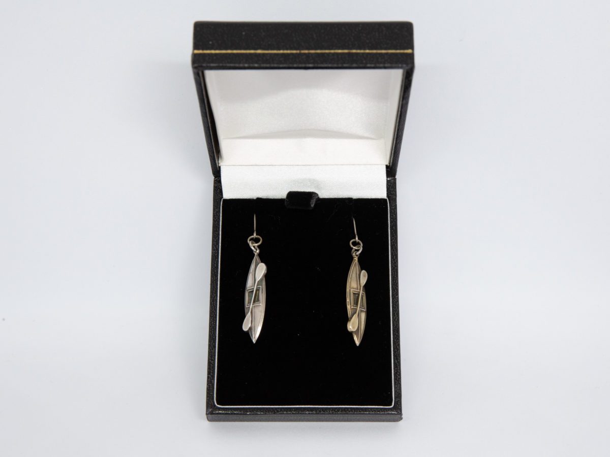 Victorian silver canoe earrings. Very unusual pair of canoe earrings with oar across the top of canoe. One canoe is silver coloured whilst other has slight golden hue and maybe gilded to distinguish 2 sides (Oxford V Cambridge perhaps?) Antique kitemark hallmark to the back of each canoe c1880. (This year being significant in that it is the only time in the history of the boat race that it was postponed for 2 days due to thick fog) Drop length approximately 45mm with canoe measuring approximately 30mm. Earrings weight 2.8gms. Box included. Photo of earrings displayed inside the box.