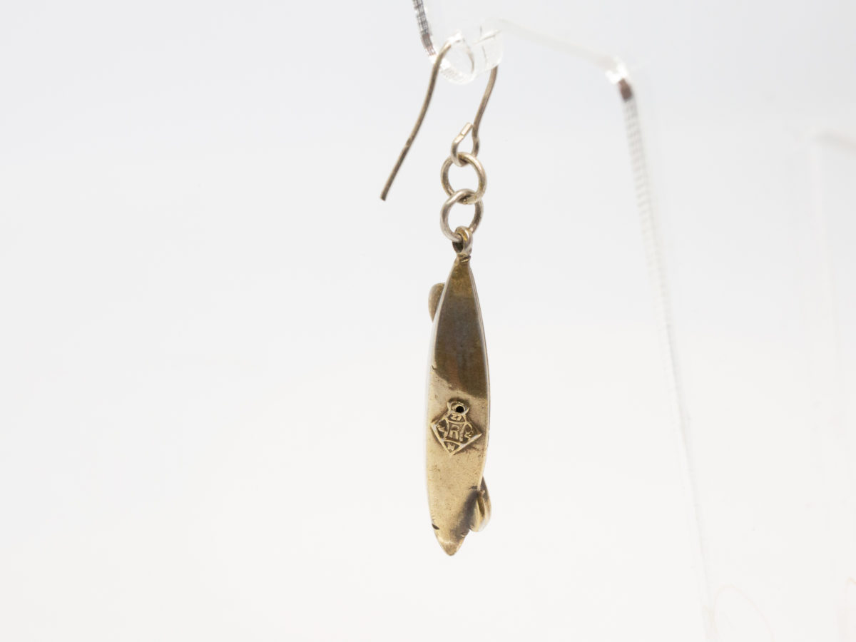 Victorian silver canoe earrings. Very unusual pair of canoe earrings with oar across the top of canoe. One canoe is silver coloured whilst other has slight golden hue and maybe gilded to distinguish 2 sides (Oxford V Cambridge perhaps?) Antique kitemark hallmark to the back of each canoe c1880. (This year being significant in that it is the only time in the history of the boat race that it was postponed for 2 days due to thick fog) Drop length approximately 45mm with canoe measuring approximately 30mm. Earrings weight 2.8gms. Box included. Close up photo of the gilt silver earring only showing the kitemark hallmark.