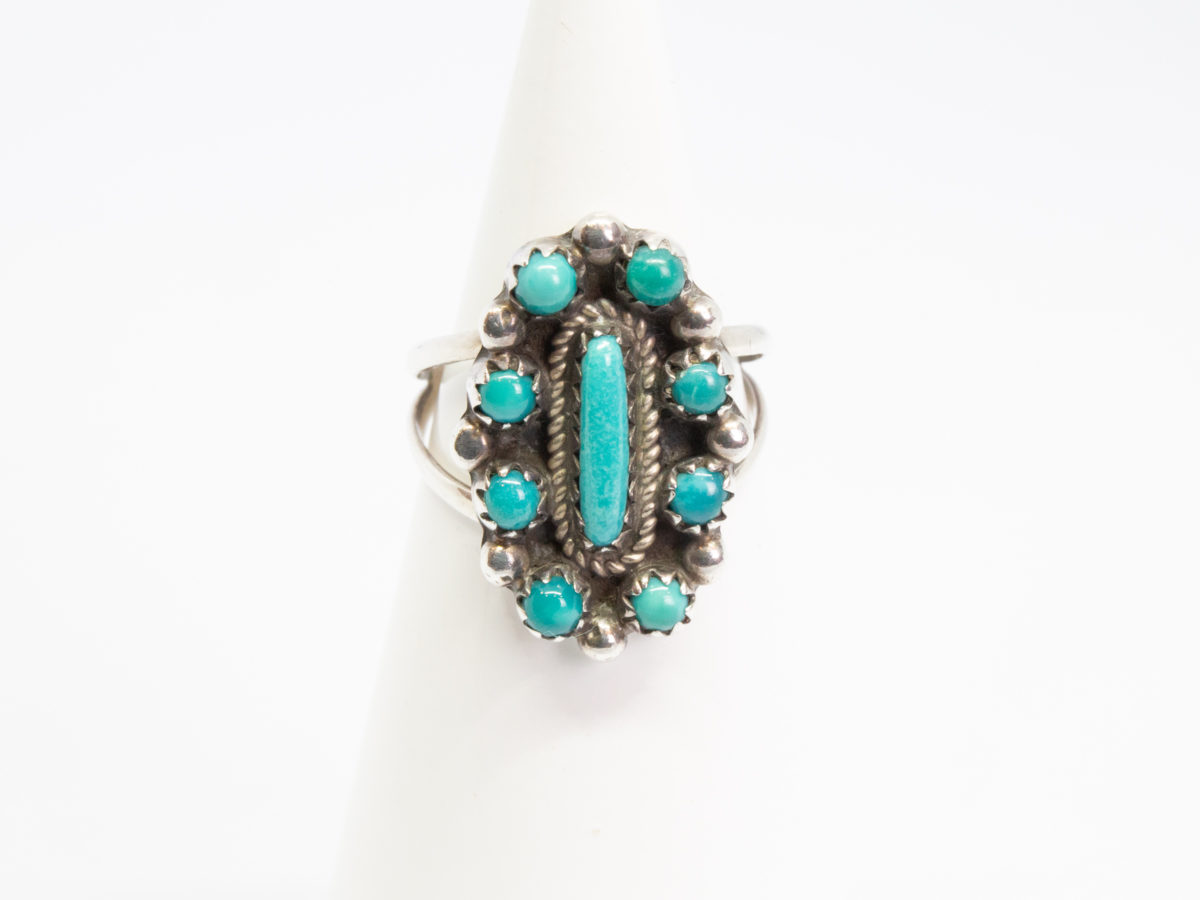 Vintage Navajo silver and turquoise ring. Sterling silver ring set with Bisbee blue turquoise. Stamped sterling with initials BB to the back for Benson Boyd. Wonderful example of fine Native American craftmanship. Ring size M / 6. Ring front measures 22mm by 15mm. Ring weight 4.3gms. Main photo of ring displayed on a cone shaped stand with ring front facing camera.