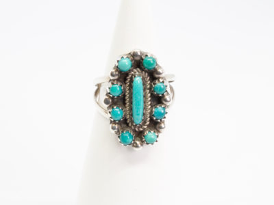 Vintage Navajo silver and turquoise ring. Sterling silver ring set with Bisbee blue turquoise. Stamped sterling with initials BB to the back for Benson Boyd. Wonderful example of fine Native American craftmanship. Ring size M / 6. Ring front measures 22mm by 15mm. Ring weight 4.3gms. Main photo of ring displayed on a cone shaped stand with ring front facing camera.