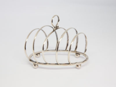Early George V silver toast rack. Small sterling silver toast rack with partitions set at a very practical diagonal angle. Full hallmark to the top of lower frame for Birmingham assay c1919 and made by George Unite. Main photo of toast rack from the side showing full length