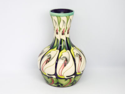Moorcroft 'lily come home' vase. Modern Moorcroft vase designed by Emma Bossons in a repeated design pattern of white lily flowers. Signed and dated to the base. Measures 80mm in diameter at base, 120mm in diameter at most bulbous part and 57mm in diameter across the top. Main photo of vase shown from a near eye level angle .