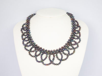 Modern black pearl necklace in a collar form. Intricately designed necklace with multiple iridescent black pearls and finished with a sterling silver clasp and slightly adjustable chain. Box included. Adjustable from approximately 400mm to 455mm. Necklace weight 57.6 grams. Main photo of necklace displayed on a stand and shown front facing.