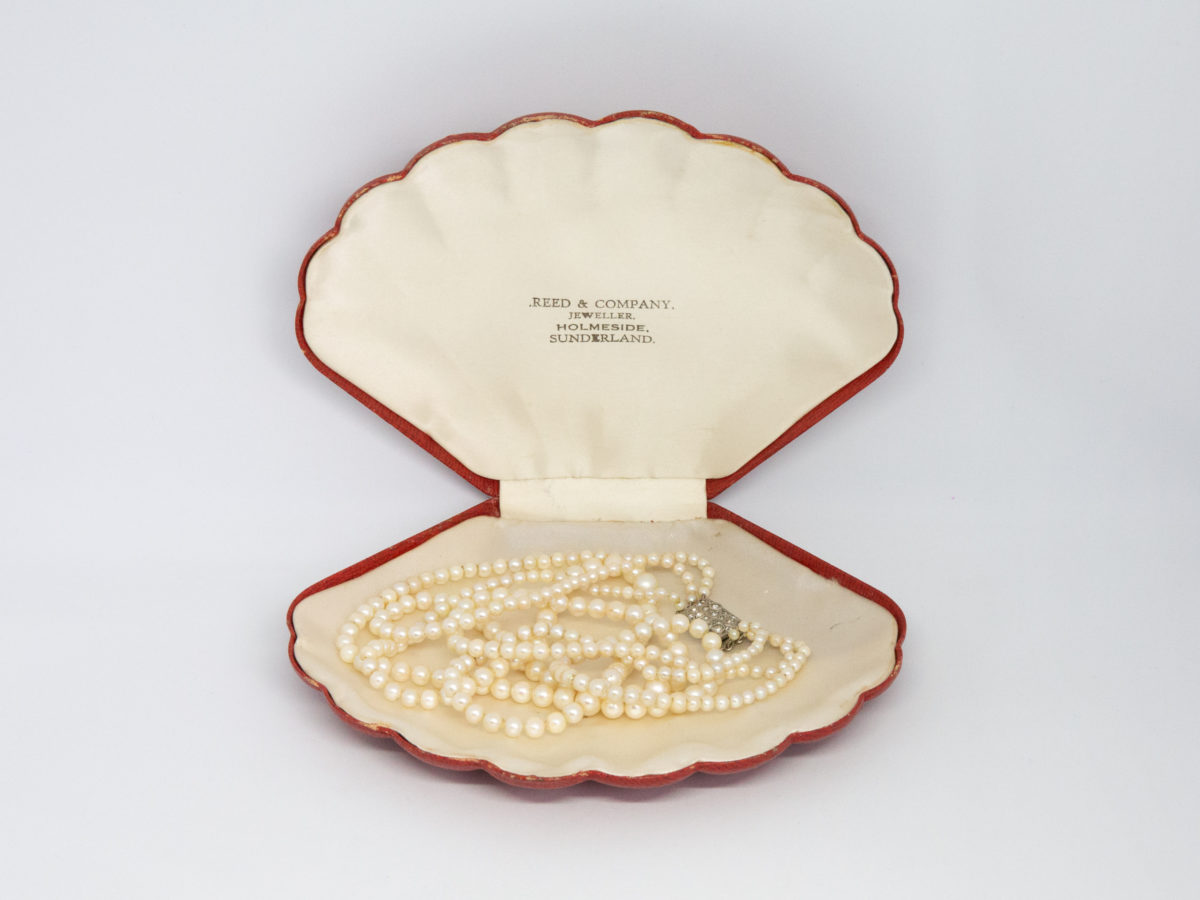 Art Deco graduated pearl necklace. Stunning necklace with 3 strands of graduated pearls and a paste stone encrusted clasp. Unidentifiable hallmark to back of clasp. Made in France. Shell shaped box included but not original. Shortest strand measures approximately 420mm and longest 450mm. Necklace weight 47gms. Photo of necklace inside the shell shaped box.