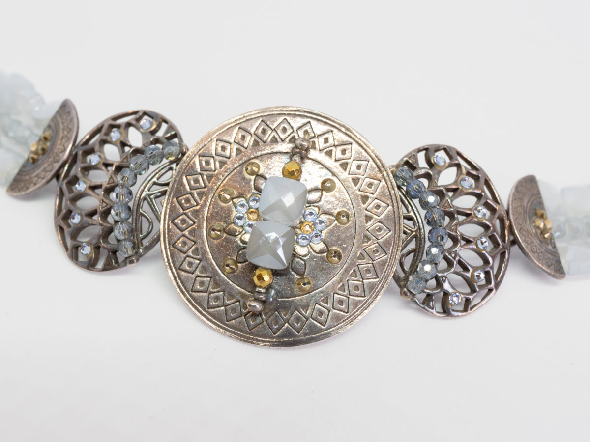 Modern Swarovski bracelet by Taratata. Very pretty bracelet evocative of ancient civilisations. Metal base set with smoky blue and gold Swarovski crystals. Made in France. Central disk measures approximately 37mm in diameter. Picture of the bracelet detailing the centre circular front with stones on it.