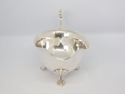 Vintage sterling silver cream or sauce jug. Simple but elegant jug with scallop detail to the legs and an open curl handle. Full hallmark to the base for Birmingham assay and made by Elkington & Co c1938. Photo of jug with spout in the centre foreground.