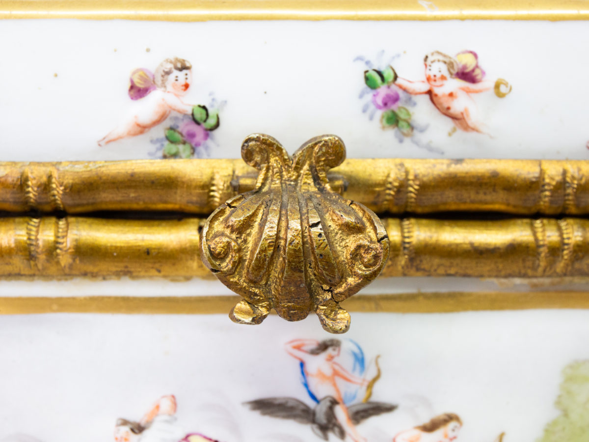 Late 19th century Naples porcelain box. A heavy porcelain box moulded in high relief with scenes of scantily clad men and women disporting themselves in various ways. Beautifully hand-painted in bright vibrant colours and finished off with gilt accent. Close up photo of the clasp looking from the front.