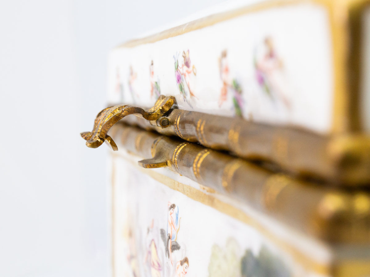 Late 19th century Naples porcelain box. A heavy porcelain box moulded in high relief with scenes of scantily clad men and women disporting themselves in various ways. Beautifully hand-painted in bright vibrant colours and finished off with gilt accent. Close up photo of clasp from a side view.
