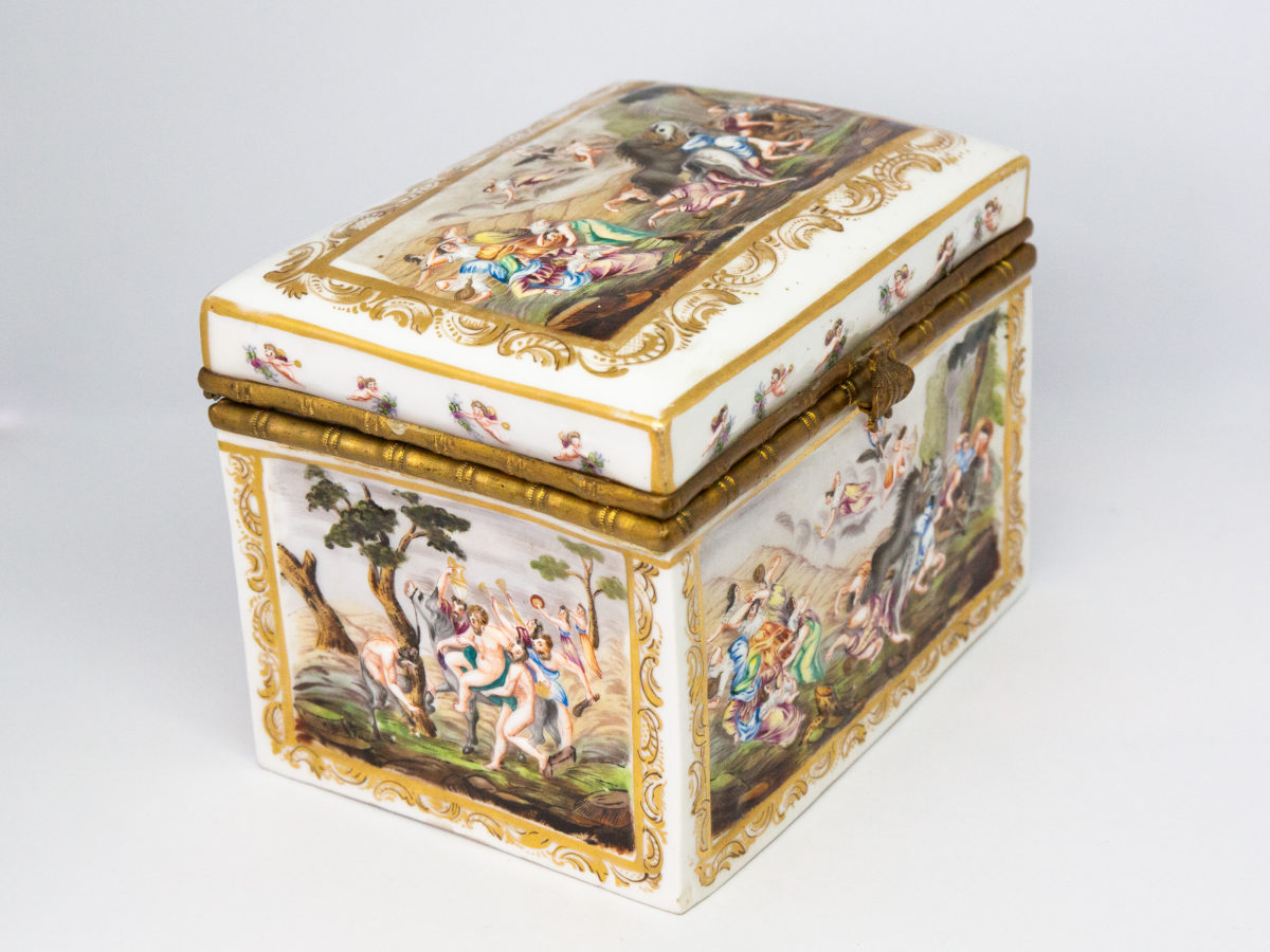 Late 19th century Naples porcelain box. A heavy porcelain box moulded in high relief with scenes of scantily clad men and women disporting themselves in various ways. Beautifully hand-painted in bright vibrant colours and finished off with gilt accent. Photo of box set diagonally with clasp front facing right & showing decoration on top, front and side.