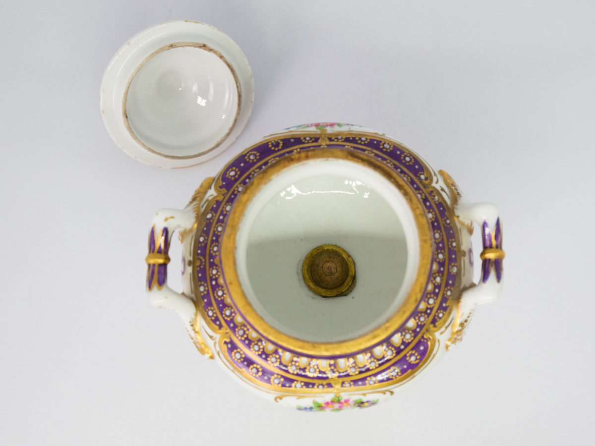 Antique Sèvres 2 handled urn with lid. Beautifully handmade and hand-painted Sèvres urn with 2 handles and lid in royal purple and gilt with floral design throughout. Some gilt wear mostly on the rim of the lid otherwise in excellent condition. Late 19th century. Base measures 55mm square, width at widest across handles 130mm, opening at top 72mm in diameter. Photo of urn with lid removed and looking down at inside. The lid is seen to the top left of photo with inside of lid shown.