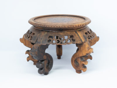 Vintage carved Chinese wooden stand. A nice sized Chinese stand in natural wood with lovely carved detail to the skirt under the stand and to the legs. Some repair work has been carried out as shown on photos. Outer diameter of top area measures 126mm and inner diameter measures 103mm. Widest area at top of legs measures 165mm. Main photo of stand shown from a near eye level angle.