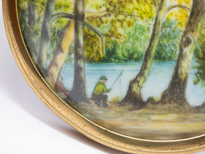 Hand-painted miniature with brass frame. Lovely hand-painted miniature of a man fishing by the river under the trees and a second person asleep. Wonderful detail to this piece of art. Measures 75mm in diameter. Drop length from top of bail measures 92mm. Close up photo of the fisherman in the picture.