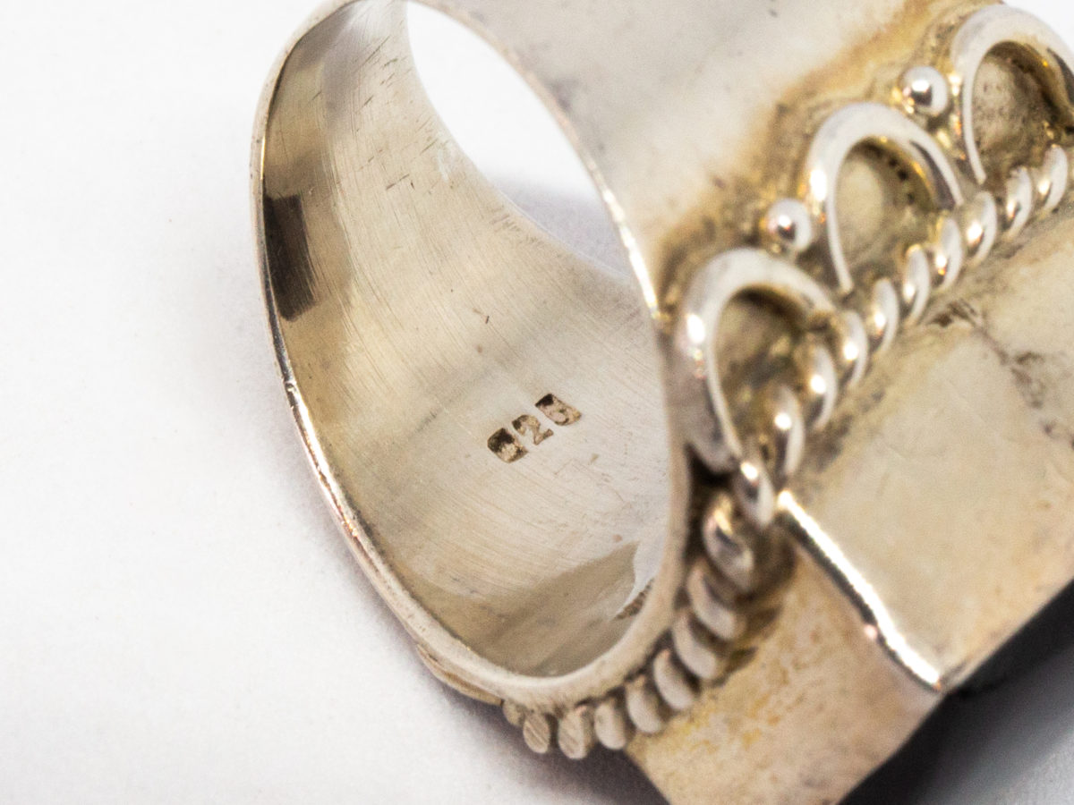 Vintage sterling silver and black onyx ring. A nice chunky sterling silver ring set with a large rectangular black onyx. Silver twist work frames the stone area. Hallmarked 925 for sterling silver. Stone measures 16mm by 12mm.  Ring size N.5-O / 7. Close up photo of the 925 hallmark on the inside band.