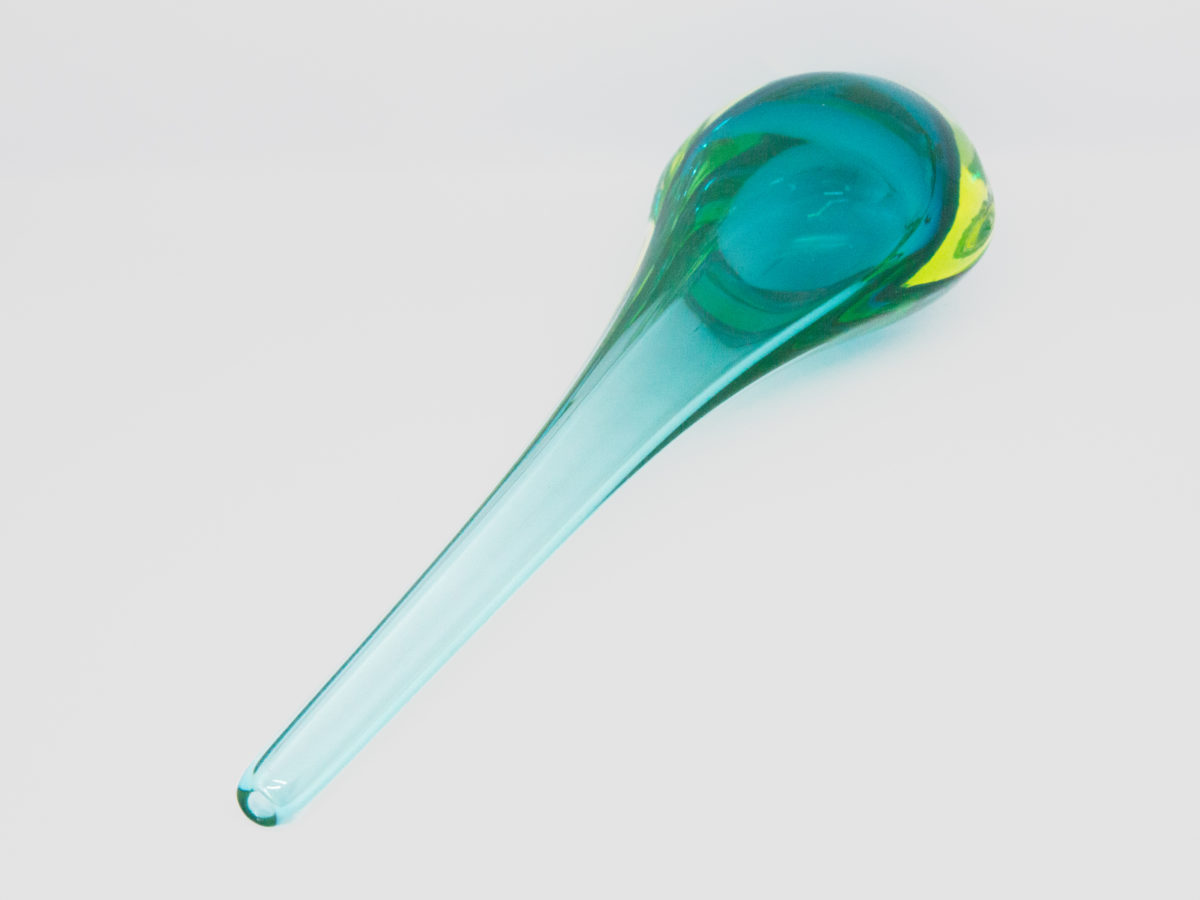 Vintage turquoise glass vase by Murano. Striking slender sommerso glass vase by Murano in stunning turquoise with vibrant sea green to the lower sides. The aesthetically stunning shape is akin to a drop of water and is very pleasing to the eye. A wonderful vintage glass art attributed to Flavio Poli. c1960s. Base measures 42mm by 30mm, the bulbous lower are measures 90mm wide by 60mm deep and top measures 12mm in diameter. The opening at top is very small measuring approximately 6mm in diameter. Photo of vase laid flat on a surface with opening end in the bottom left foreground.