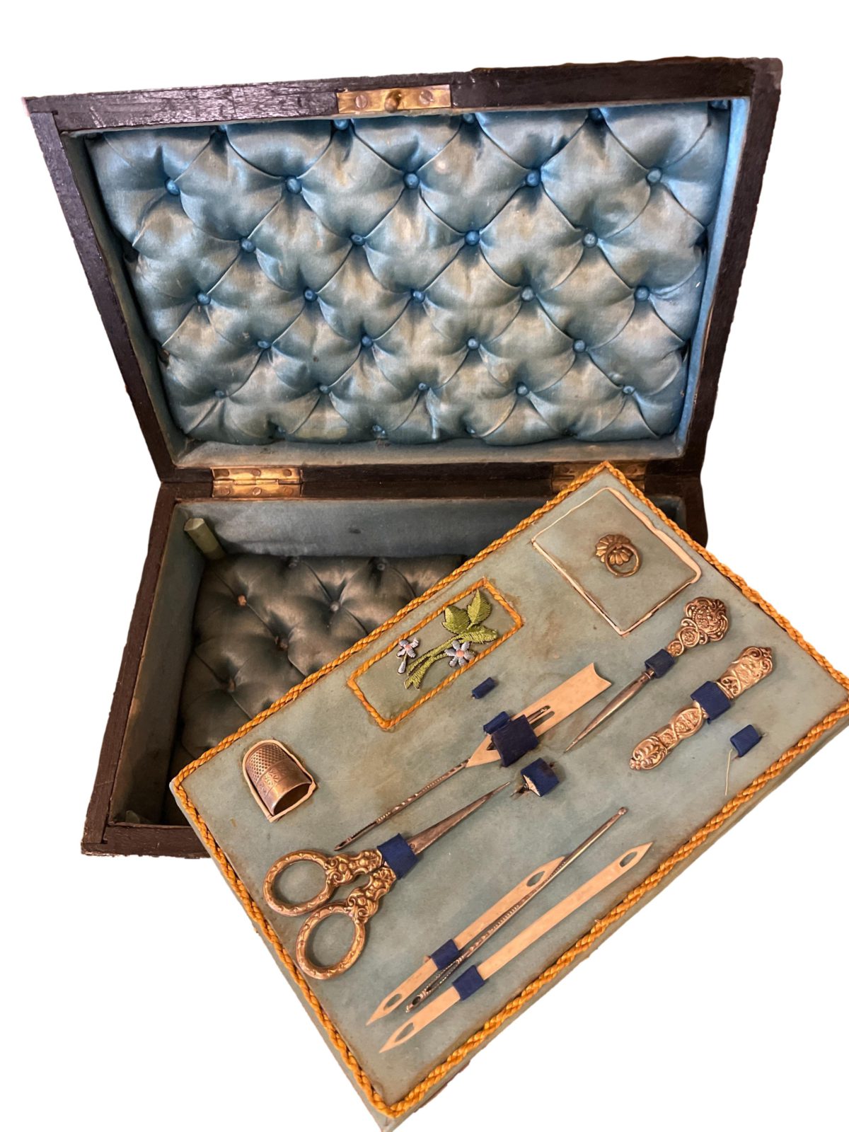 Napoleon Palais Royale sewing box with key and part original contents. Ebonised wood exterior with tulip wood veneer, brass inlay and cartouche. The inside is  lined with padded pale blue silk to the lid and base with removable tray housing the sewing tools. Napoleon III 1850-1899. Photo of open box with tool tray removed and placed on the edge to show the padded blue silk underneath tray.