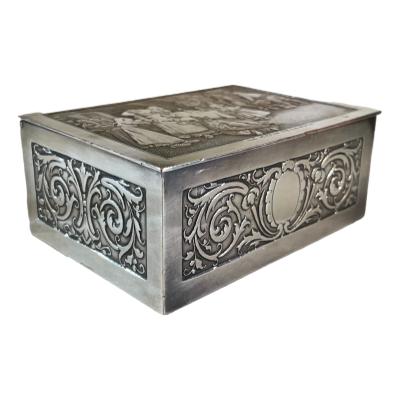 An engraved silver plate on copper French jewellery box . It dates from about 1900-1940.The lid is engraved with ‘The morning of the bridal party ( Le matin de la noce)’. There is considerable wear to the plate on the lid that allows the underlying copper to shine through also minor wear to the base. The box has its a original padded satin interior with a little wear to the silk. The box weighs 298grams. Photo of box with front facing right.
