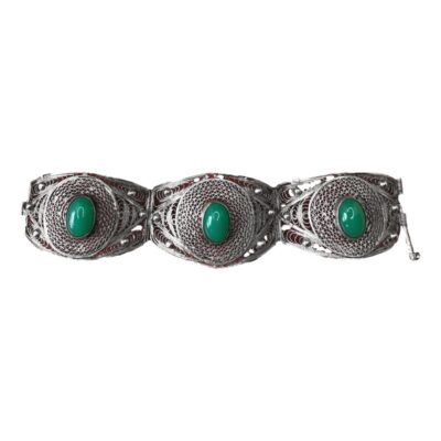 An Art Deco silver filigree bracelet. Each panel of the bracelet is stamped with the Egyptian hallmark for 800 silver and the date letter O for the period 1938-1939. There is a green chrysoprase cabochon stone in the centre of each panel. It is secured with push pin closure and weighs 39.8 grams. Main photo of bracelet laid out in a straight line from left to right showing all 3 panels with cabochons to the centre of each.